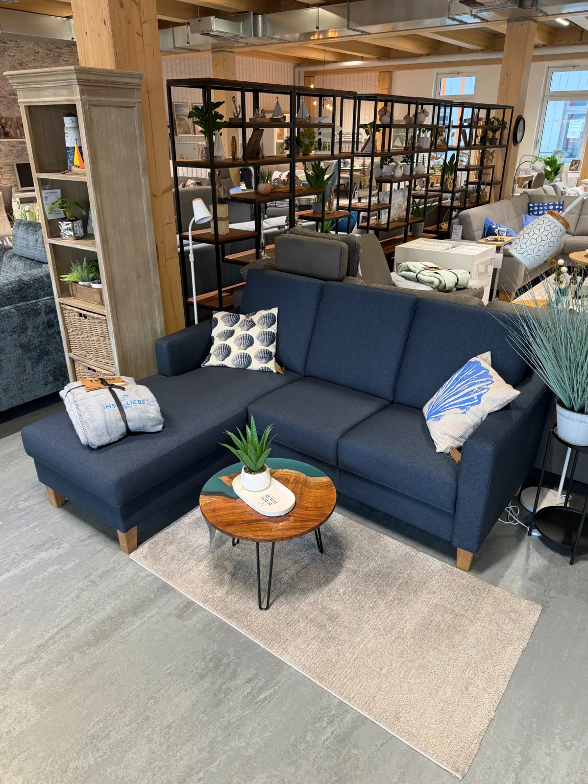 Kompaktes dunkelblaues Ecksofa mit Kissen und rundem Couchtisch