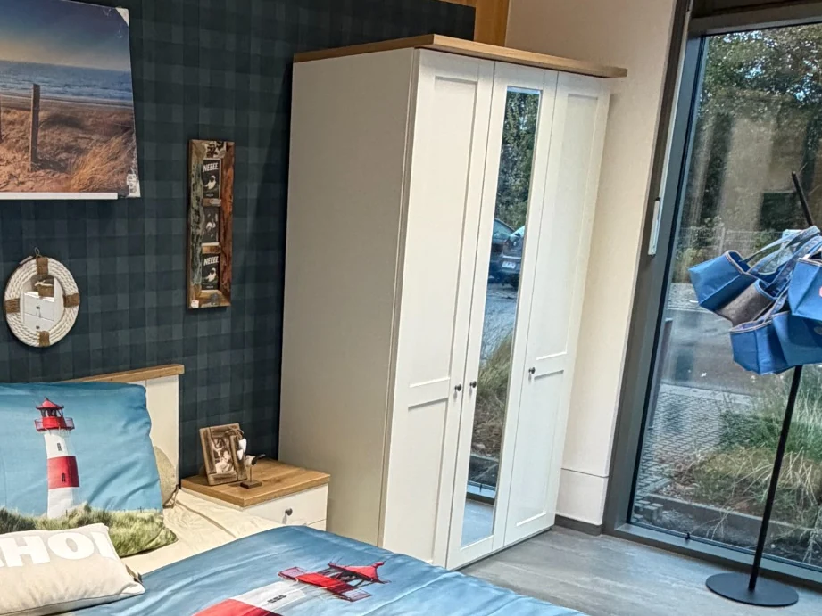 Weißer Kleiderschrank mit Spiegeltür und Holzdetails im liege.platz auf Föhr
